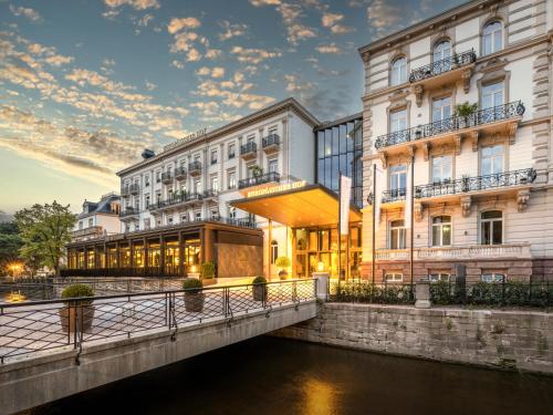 a hotel with a bridge over a river at Steigenberger Icon Europäischer Hof Baden Baden in Baden-Baden