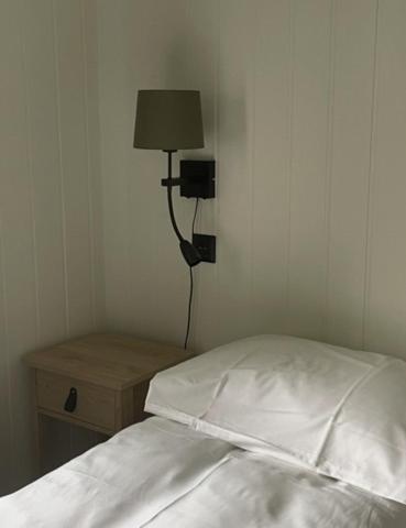 a bedroom with a bed and a lamp on a night stand at Thunehuset in Andøya