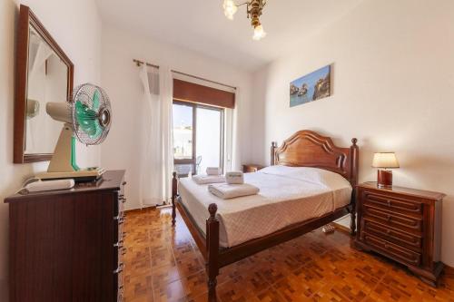a bedroom with a bed and a dresser and a window at Bairro Apartment in Lagos in Lagos