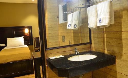 a bathroom with a sink and a bed at Ranis Grand in Coimbatore