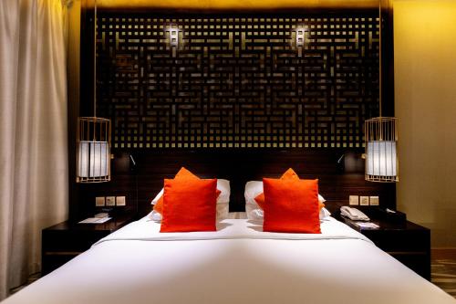 a bed with two orange pillows in a room at Ramada Hotel & Suites by Wyndham Al Qassim in Al Bukayriyah