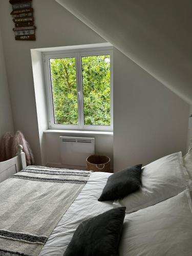 a bedroom with a bed with pillows and a window at Maison Jazharra -SPA - 6 - 8 pers - Proche Golf in Frehel