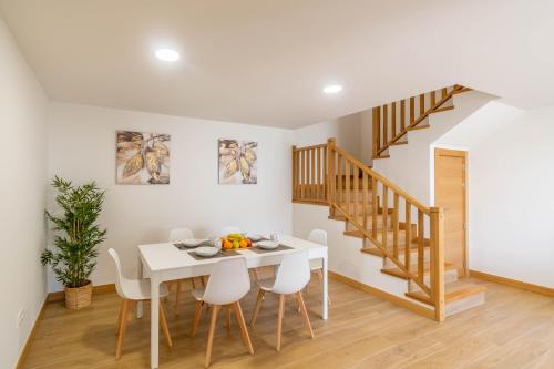 a dining room with a white table and a staircase at Amplia casa rural con barbacoa y jardín en Navarra in Olcoz