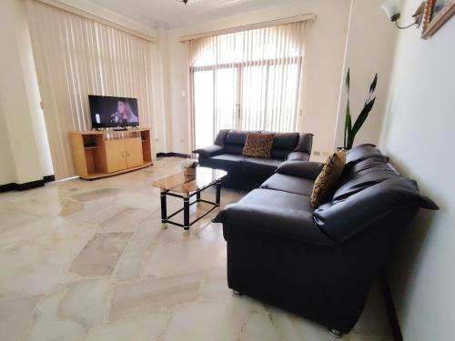 a living room with a black couch and a tv at Del Sol Suites - Guayaquil in Guayaquil