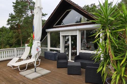 a deck with a lounge chair and an umbrella at Traumferienwohnung in Hitzacker ot Bahrendorf in Bahrendorf