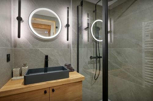 a bathroom with a sink and a shower with a mirror at Chalet Belle Source A - OVO Network in Saint-Nicolas-la-Chapelle