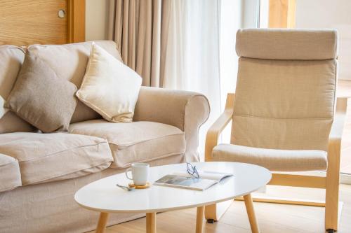 ein Wohnzimmer mit einem Stuhl und einem Couchtisch in der Unterkunft Amplia casa rural con barbacoa y jardín en Navarra in Olcoz