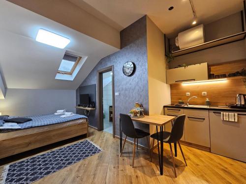 a bedroom with a bed and a table and a kitchen at Hidden Gem in Novi Sad