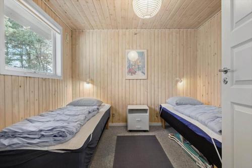 2 Betten in einem Zimmer mit Holzwänden und einem Fenster in der Unterkunft 1542 Aakirkeby - Poseregårdsvejen 12 in Vester Sømarken