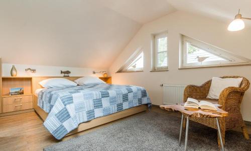 a bedroom with a bed and a chair and windows at Wellenzauber in Ahrenshoop