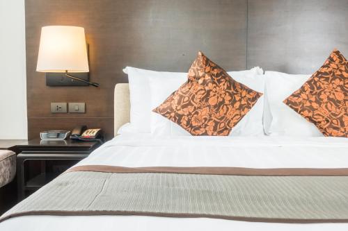a bed with pillows and a lamp on a table at Hotel Luxury Villas Near IGI Delhi Airport in New Delhi