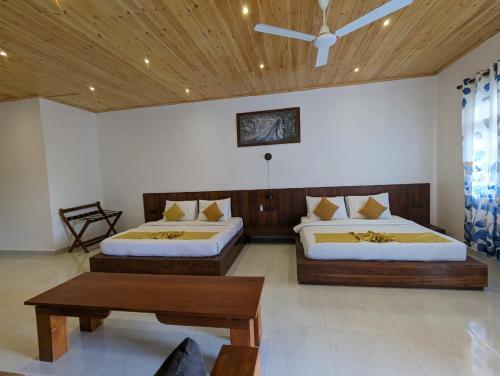 a bedroom with two beds and a wooden ceiling at Eco Hotel Black & White - Anuradhapura in Mihintale