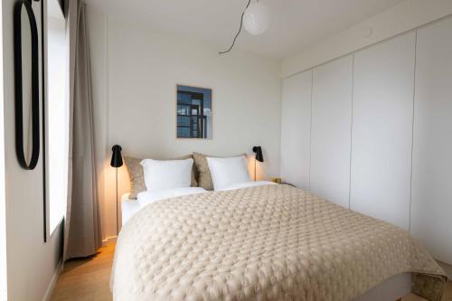 a bedroom with a large bed with white walls at Cozy 9th Floor Apartment in Vesterbro in Copenhagen