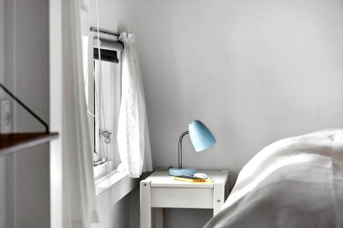 a bed with a lamp on a nightstand next to a window at 6619-Allinge-Markvejen-45 in Allinge