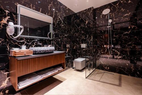 bagno nero con lavandino e specchio di Iliria Hill Resort & Spa a Orllan