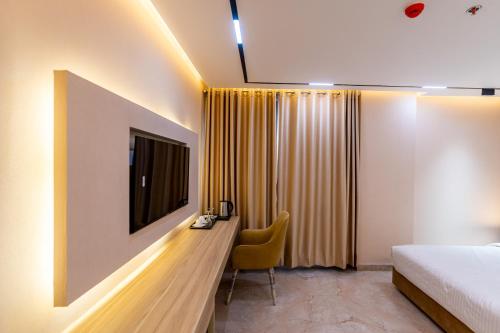 a bedroom with a bed and a desk with a television at Emerald Dhaka Luxury Hotel in Dhaka
