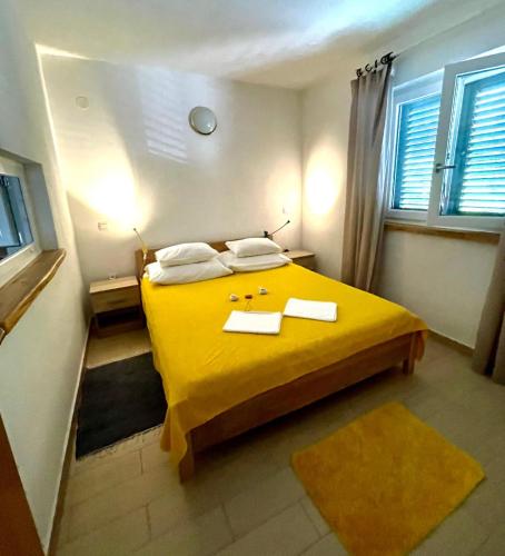 a bedroom with a yellow bed with two towels on it at Ribarica GO green 2 in Ribarica