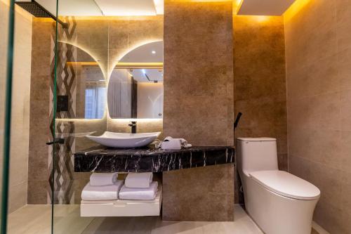 a bathroom with a sink and a toilet and a mirror at Emerald Dhaka Luxury Hotel in Dhaka