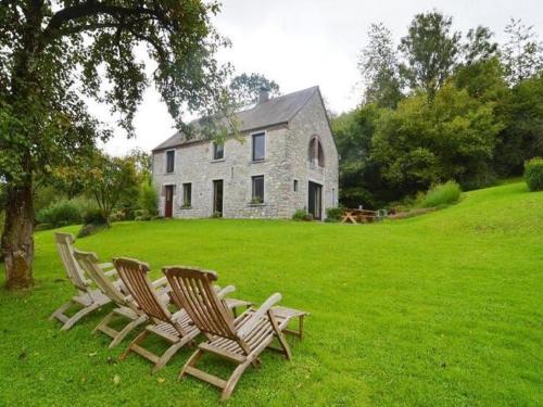a group of chairs sitting in the grass in front of a house at Chimay Nature Hideaway in Chimay