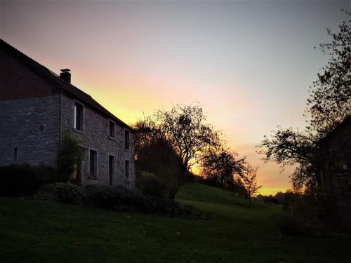an old house on a hill with the sunset in the background at Chimay Nature Hideaway in Chimay