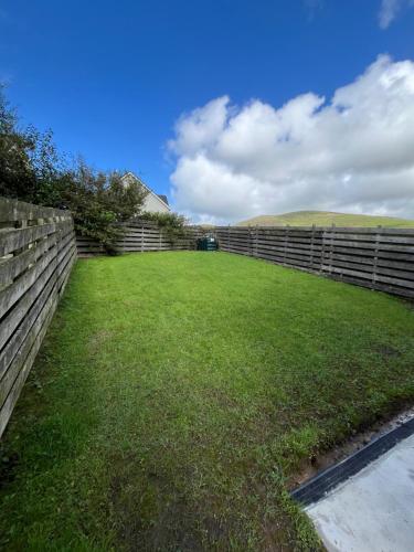 a yard with a fence and a green field at 2 Cois Chnoic - Dingle holiday home in Dingle