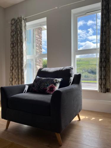 a couch in a living room with two windows at 2 Cois Chnoic - Dingle holiday home in Dingle