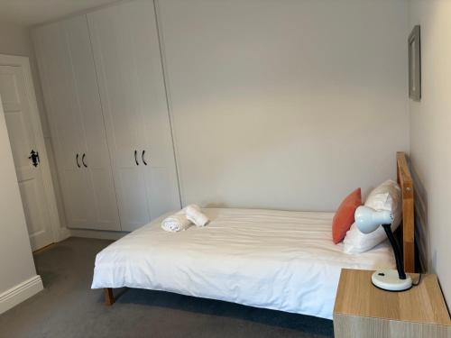 a bedroom with a white bed with a lamp on a table at 2 Cois Chnoic - Dingle holiday home in Dingle