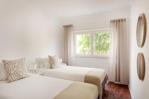 a white room with two beds and a window at Estoril Beach - Your Family Escape in Estoril