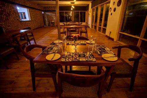 a wooden table in a restaurant with plates and glasses on it at Burunga Gorilla Lodge in Kisoro