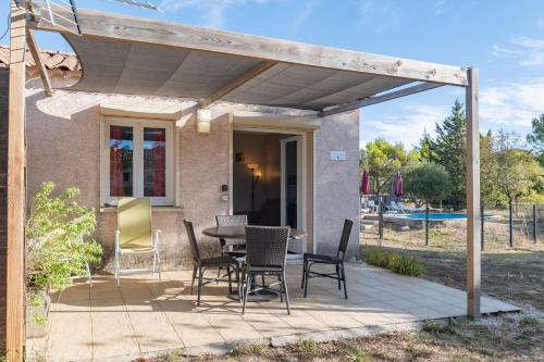 a patio with a table and chairs under a pergola at Gîte Chêne ou Murier in Les Vans