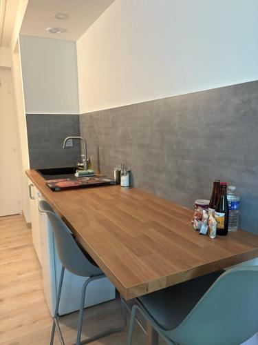 a kitchen with a wooden counter top with two chairs at Le Phoenica - Former Hotel - Parking in Carquefou