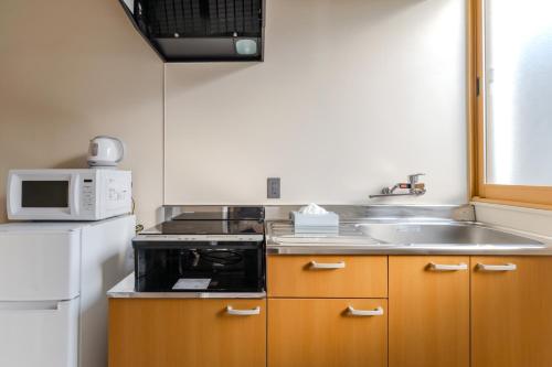 a small kitchen with a sink and a microwave at 楽途ホテル 東十条 in Tokyo
