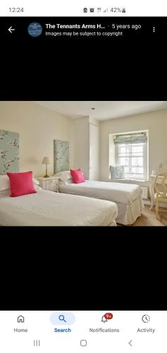 two beds with pink pillows in a room at The Tennants Arms Kilnsey in Grassington