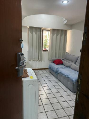 Una sala de estar con un sofá azul y una ventana. en Flat Pasárgada III (apt 116), en Vila Velha
