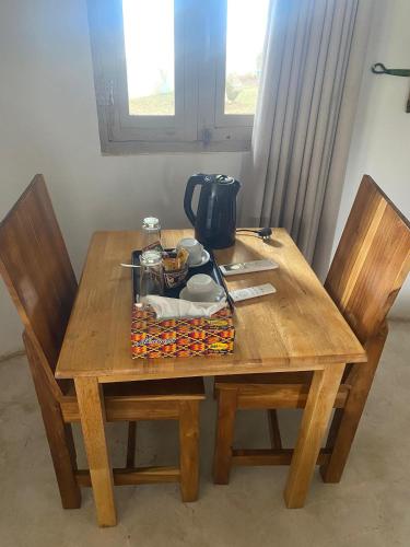 a wooden table with two chairs and a tea pot on it at Oasis beach resort in Cape Coast