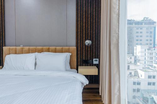 a bedroom with a bed with a view of a city at Emerald Dhaka Luxury Hotel in Dhaka