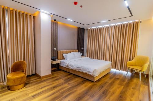 a bedroom with a bed and two chairs in it at Emerald Dhaka Luxury Hotel in Dhaka