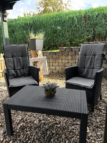 two chairs and a table on a gravel patio at FeWo Seelücke in Munkbrarup