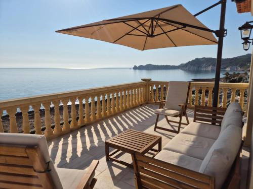 a balcony with chairs and an umbrella and the ocean at Mar-Beach front apartment in Jávea in Jávea