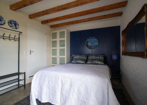 a bedroom with a white bed with a blue wall at Hemhuisje in Zaandam