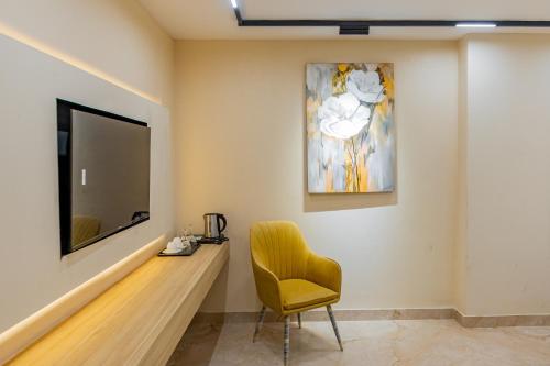 a living room with a yellow chair and a television at Emerald Dhaka Luxury Hotel in Dhaka