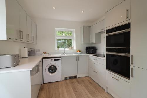 a kitchen with white cabinets and a washer and dryer at Round House view in Chesterfield