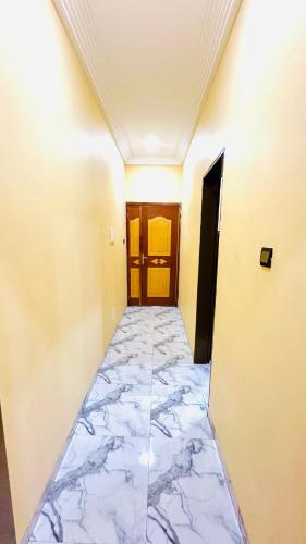 an empty hallway with a marble floor and wooden doors at RESIDENCE PHs 2 in Ouagadougou