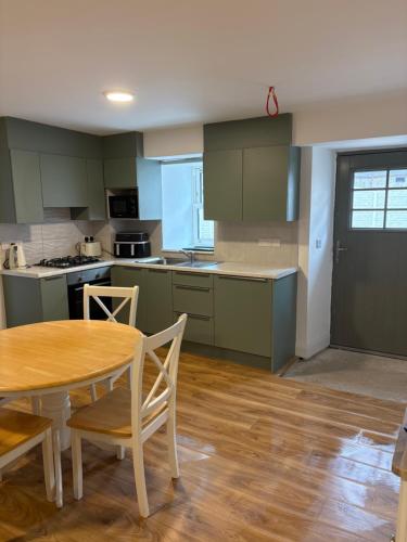 a kitchen with green cabinets and a table and chairs at The Courtyard Apartments in Macroom