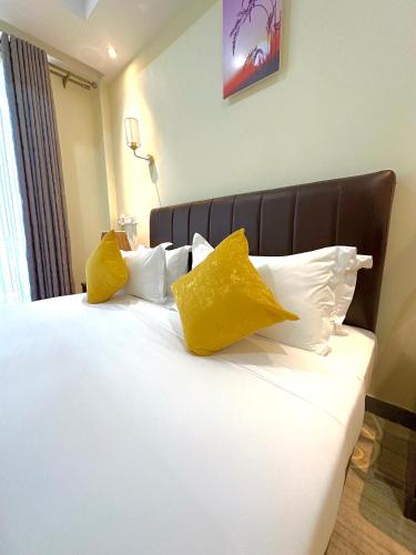 a white bed with yellow pillows on top of it at KIjichi gateway Hotel in Dar es Salaam
