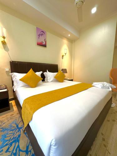 a bedroom with a large white bed with yellow pillows at KIjichi gateway Hotel in Dar es Salaam