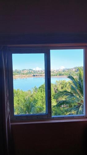 a window with a view of a body of water at CHAMBRE LA TERRASSE Nosy-be in Hell-Ville