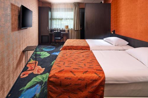 a hotel room with a large bed and a desk at Hotel Babylon Heerhugowaard - Alkmaar in Heerhugowaard