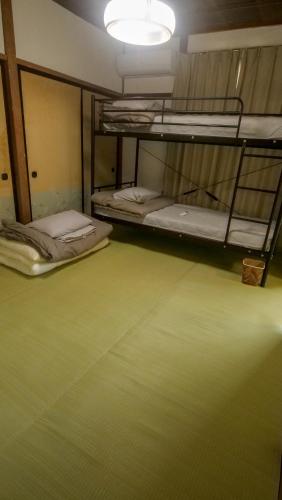 two bunk beds in a room with a green floor at 木の家ゲストハウス郡山別館 in Koriyama