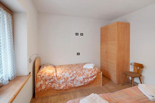 a bedroom with a bed and a wooden cabinet at Appartamento Nuovo A San Giovanni in Pozza di Fassa